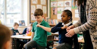 Enfants réalisant des mouvements croisés de Brain Gym dans une salle lumineuse
