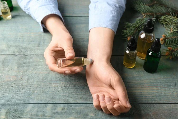 Femme appliquant de l'huile essentielle sur un poignet à une table en bois, gros plan