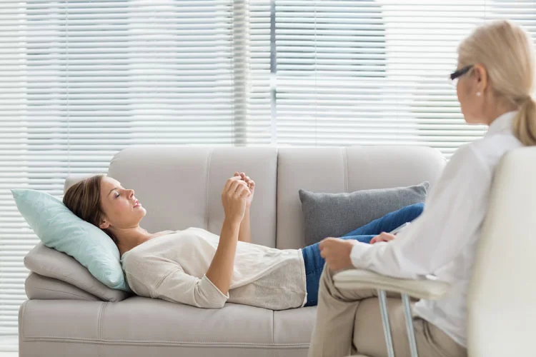 Femme parlant à un thérapeute, allongée sur un canapé