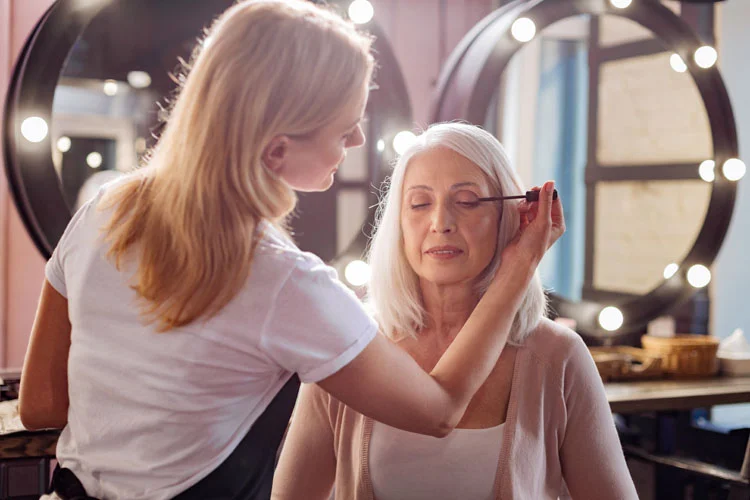 Une styliste personnelle applique du mascara sur les cils d'une femme.