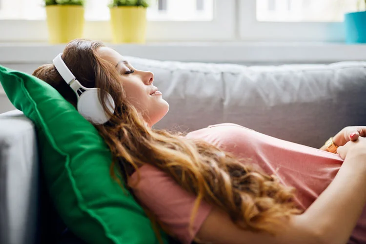 Jeune fille écoutant de la musique sur un canapé