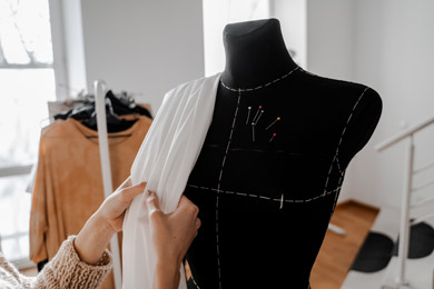 Des mains qui trient le tissu. Mannequin avec du tissu sur le