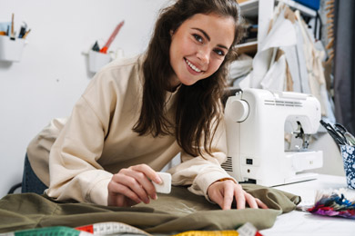 Portrait d'une couturière heureuse en train de coudre dans l'atelier